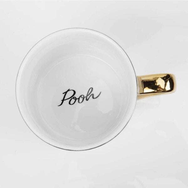 White mug with gold handle and 'Pooh' text on a white background