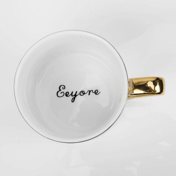 White mug with gold handle and 'Eeyore' text on a white background