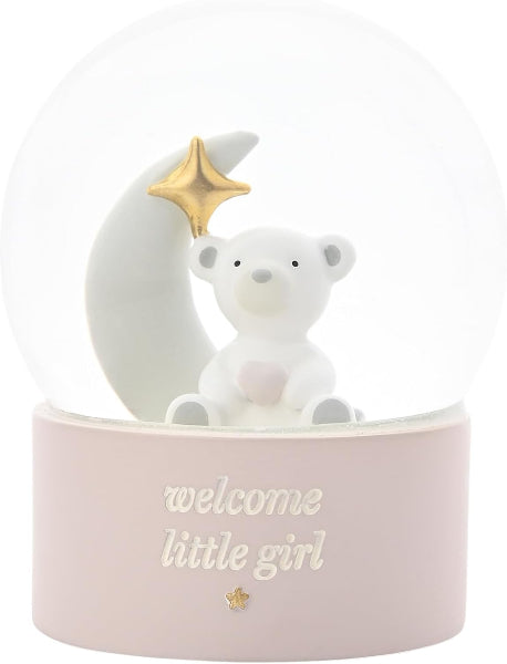 A white ceramic snow globe featuring a white teddy bear sitting on a crescent moon with a gold star, set in a pale pink base with the text 'welcome little girl'.