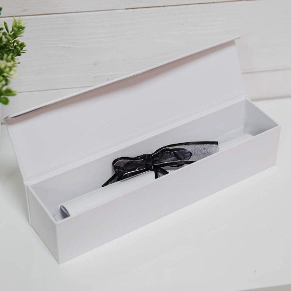 Black bow tie inside an open white box on a light wooden surface.