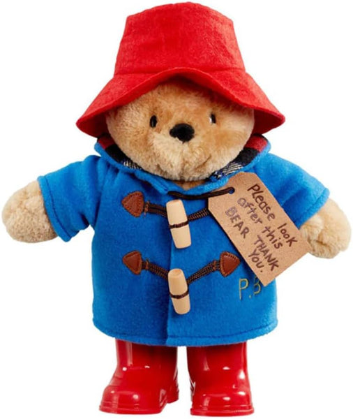 Plush toy bear in a blue coat, red hat, and boots with a tag on a white background