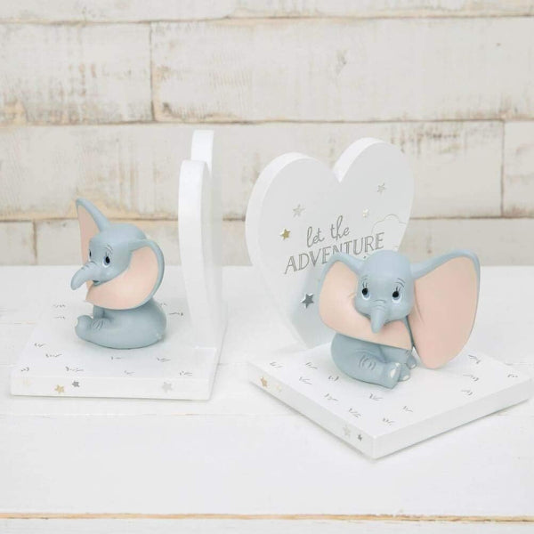 Two elephant figurines and a heart-shaped sign with 'let the adventure begin' text on a wooden surface.