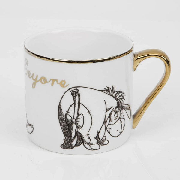 White mug with gold rim and handle featuring a black illustration of a donkey and the word 'Eeyore'.