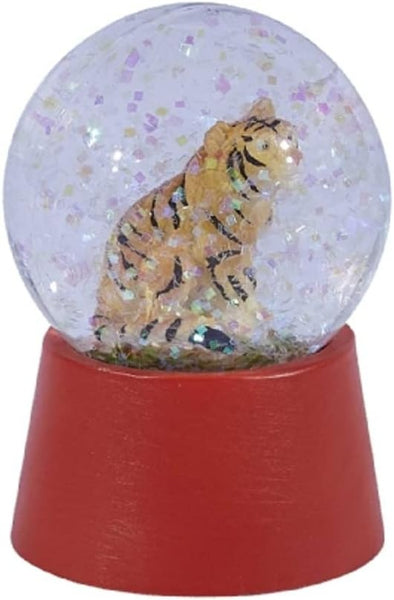 A tiger snow globe figurine featuring a small seated tiger inside a clear glittery sphere on a red base, isolated on a white background.