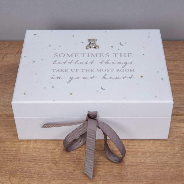 White decorative box with text and a ribbon on a wooden surface