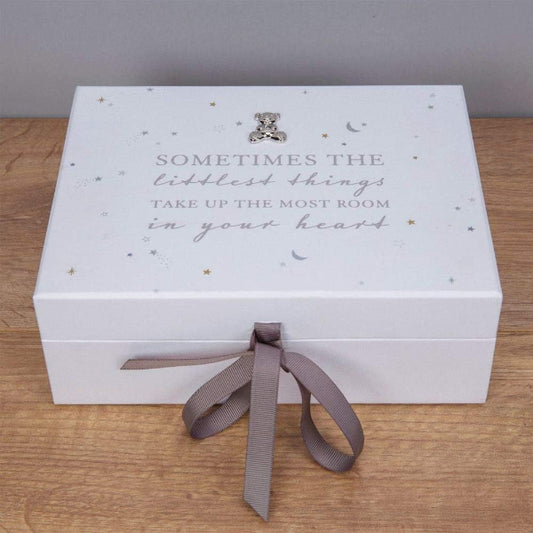 White decorative box with text and a ribbon on a wooden surface