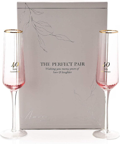 Two pink champagne flutes with gold rims in front of a 'The Perfect Pair' box.