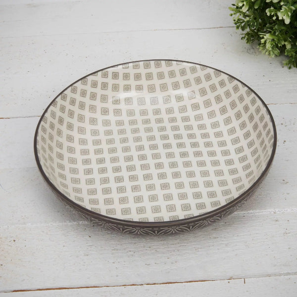 Decorative ceramic bowl with geometric pattern on a white wooden surface