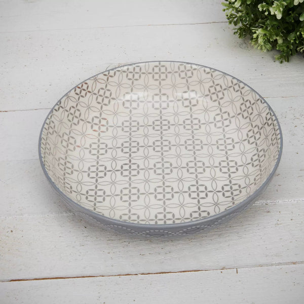 Round ceramic plate with geometric pattern on a white wooden surface