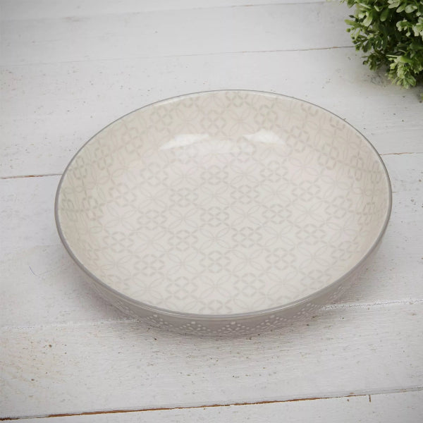 Round ceramic plate with textured surface on a light wooden floor