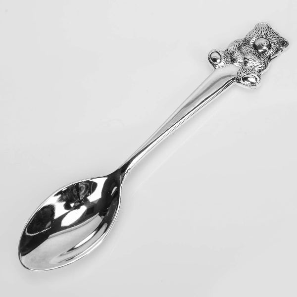 Silver spoon with decorative handle on a light gray background