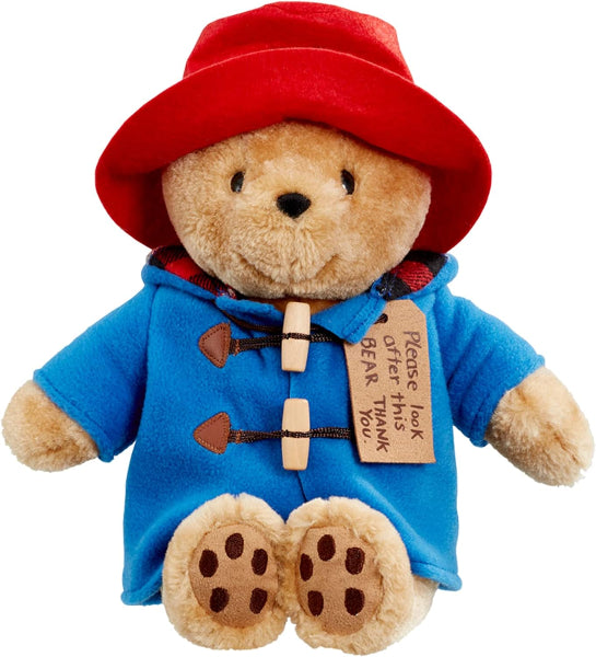 Plush toy bear in a blue coat and red hat with a tag, on a white background