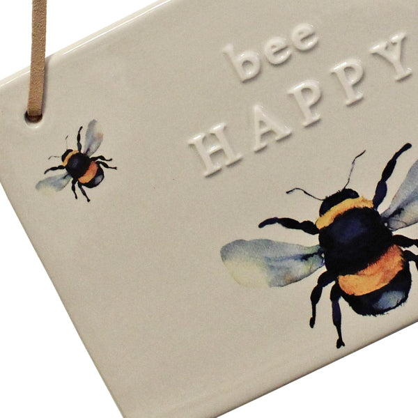 Decorative sign with bees and 'bee happy' text on a beige background