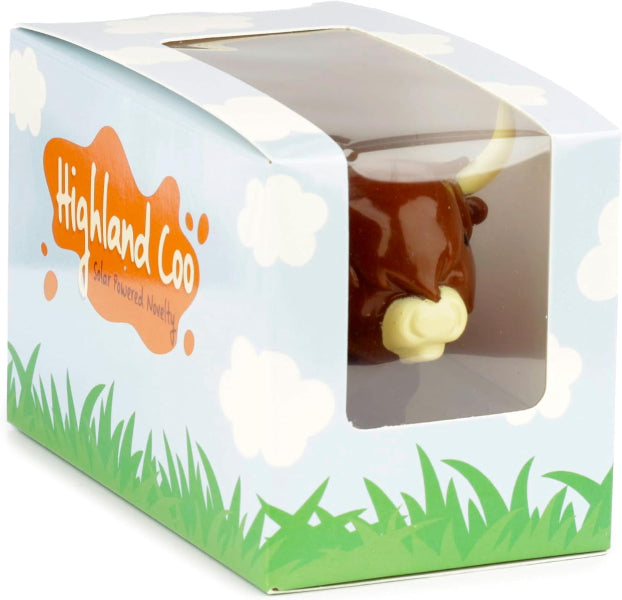 Toy cow in a 'Highland Coo' branded box with a grassy design.