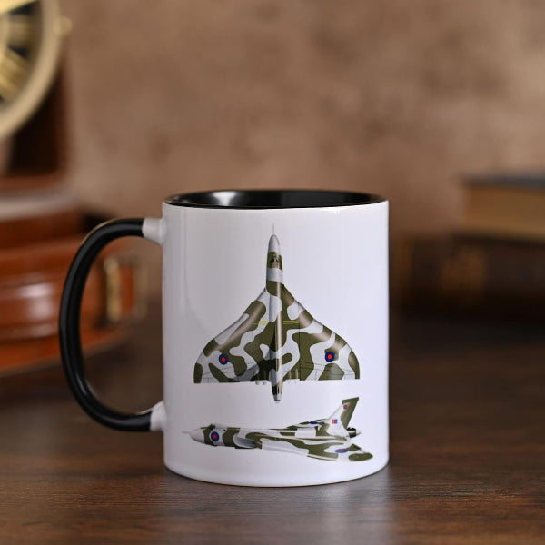 White mug with black interior and handle featuring a camouflage airplane design on a wooden surface.