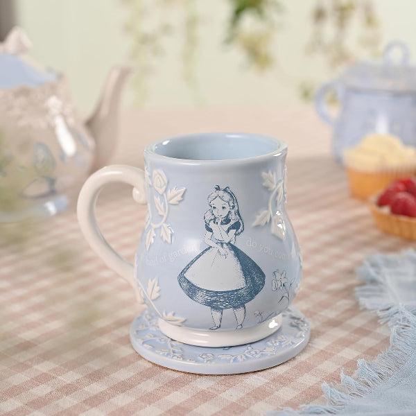 Blue mug with Alice in Wonderland design on a checkered tablecloth