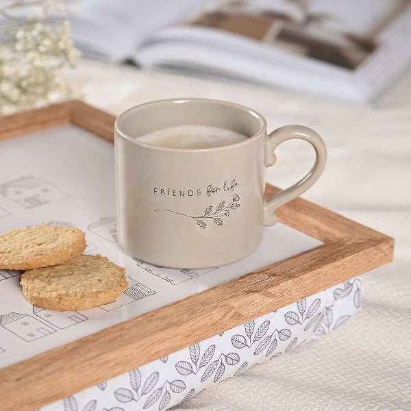 Beige mug with 'Friends for Life' text on a wooden tray with cookies