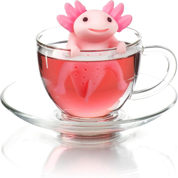 Pink axolotl-shaped tea infuser in a glass of red liquid on a white background