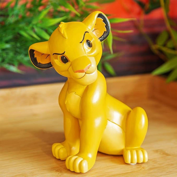 Yellow lion figurine on a wooden surface with plants in the background