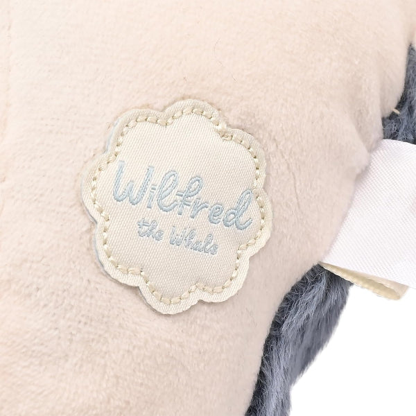 Plush toy with a label reading 'Wilfred the Whale' on a light background
