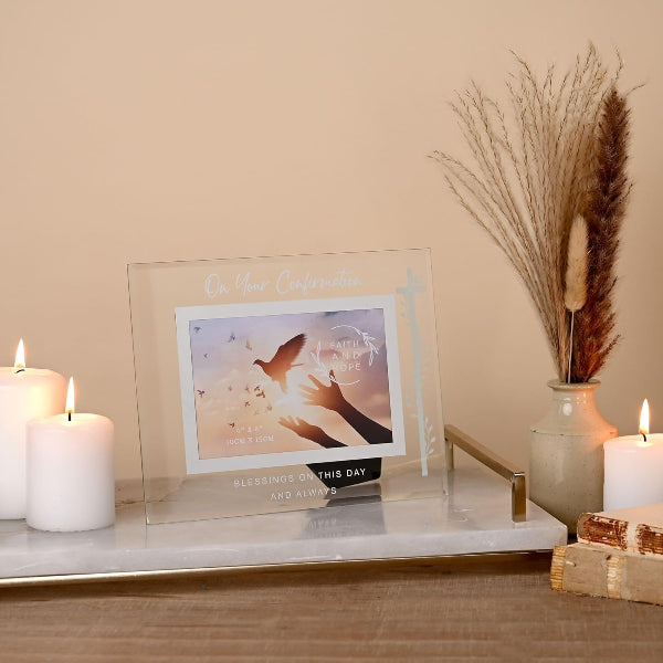 Decorative setup with a clear acrylic photo frame, candles, and dried plants on a marble surface.
