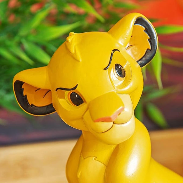 Yellow toy figure of a lion cub with a blurred green and red background