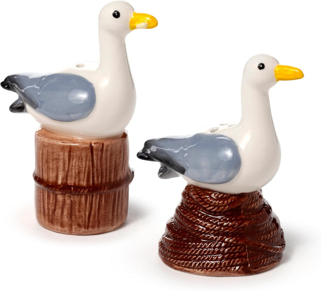Two ceramic seagull salt and pepper shakers on wooden bases with a white background.