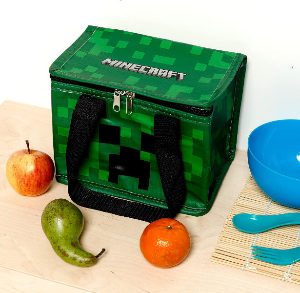 Green Minecraft lunch bag with fruits and utensils on a white background