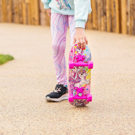 Child holding a colorful skateboard with cartoon characters on a paved path.