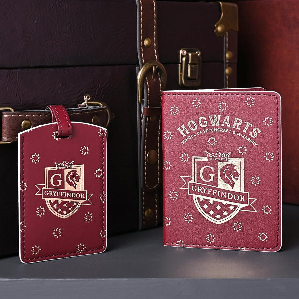 Red Gryffindor-themed luggage tag and passport holder on a dark surface with a suitcase in the background.