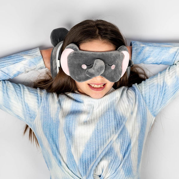 Person wearing a gray elephant-shaped eye mask and a blue and white patterned blanket