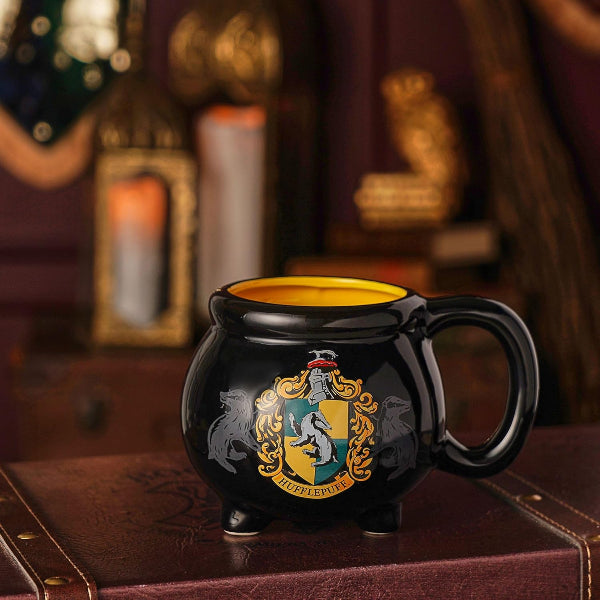 Black mug with a yellow interior, featuring a crest design, on a dark background.