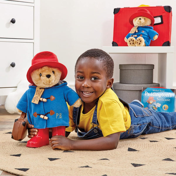 Child playing with a Paddington Bear toy on a carpeted floor.