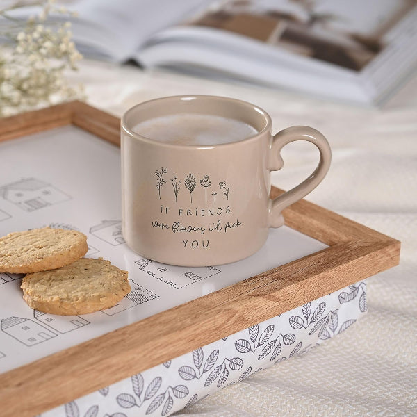 Beige mug with floral design and text on a wooden tray with cookies