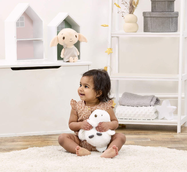 Child holding a plush toy in a room with shelves and toys