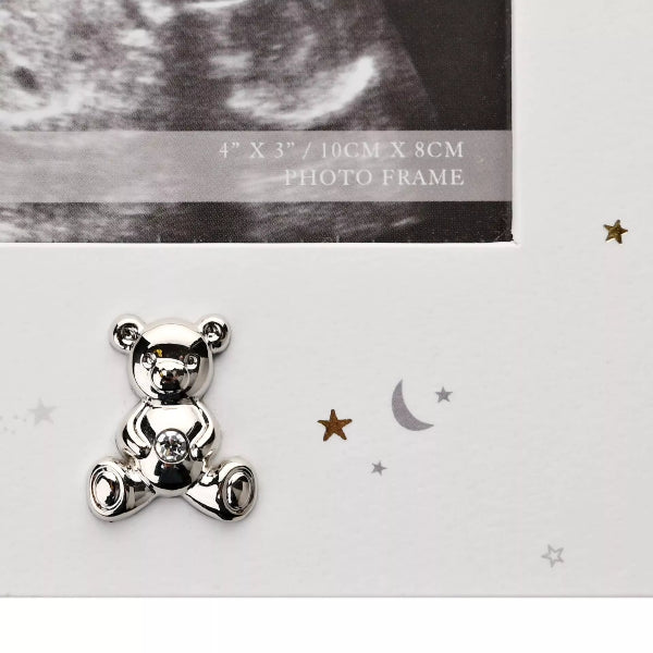 Silver teddy bear charm on a white background with decorative elements.