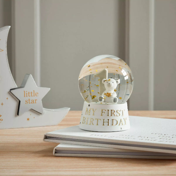 Glowing snow globe with a bear and 'My First Birthday' text on a wooden surface.