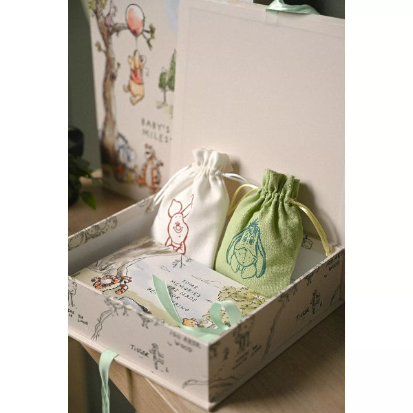 Two drawstring bags, one white and one green, on a box with cartoon character designs.