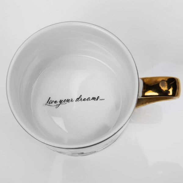 White mug with gold handle and 'live your dreams' text on a white background