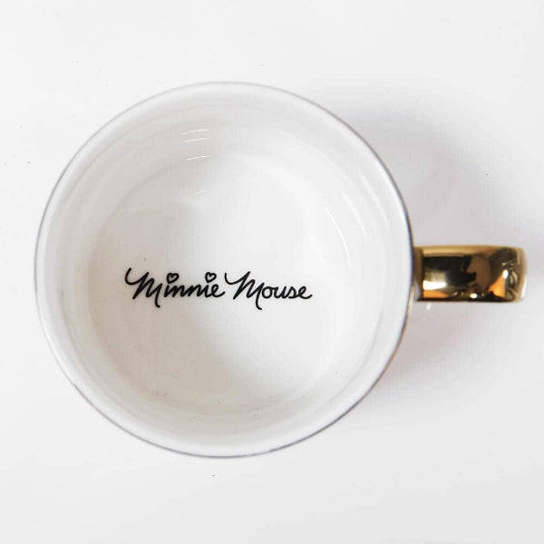 A white ceramic mug viewed from above, featuring the text 'Minnie Mouse' printed in black script inside the cup and a shiny gold metallic handle on the right side.