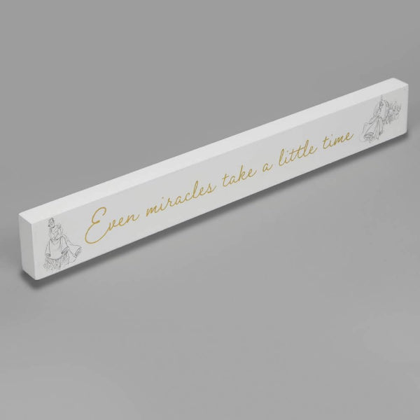 Decorative white plaque with gold text and illustrations on a gray background