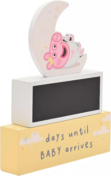 Decorative pregnancy countdown item with a piggy bank and moon on top, displayed on a stand.