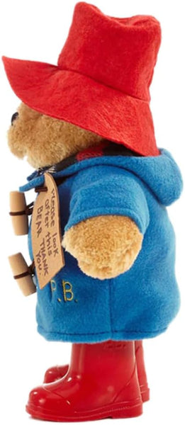 Plush toy bear in a blue coat, red hat, and boots with a tag on a white background