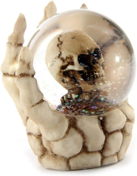 Decorative piece with a skeleton hand holding a crystal ball containing a skull on a white background
