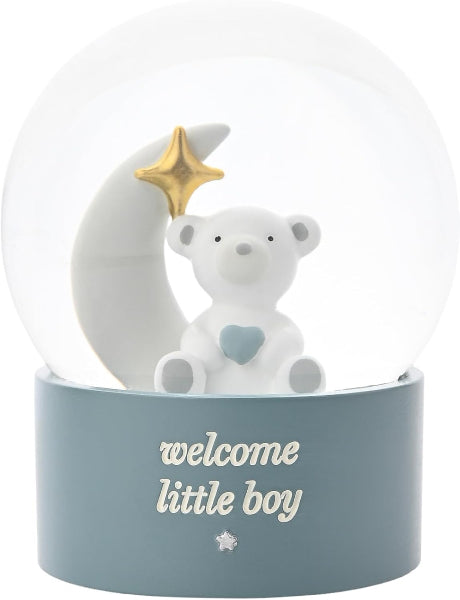 A white ceramic 'Welcome Little Boy' snow globe figurine featuring a teddy bear with a light blue heart, a white crescent moon, and a gold star, set in a dusty blue base with white text.