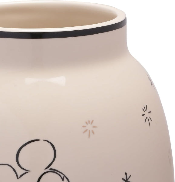 Close-up of a beige ceramic jar with black decorative elements on a white background