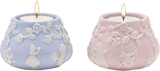 Two lit candles in decorative ceramic holders with floral patterns.