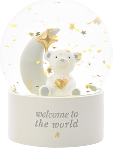 A white bear and crescent moon snow globe decoration with gold star accents and the text 'welcome to the world' on the base, shown against a white background.