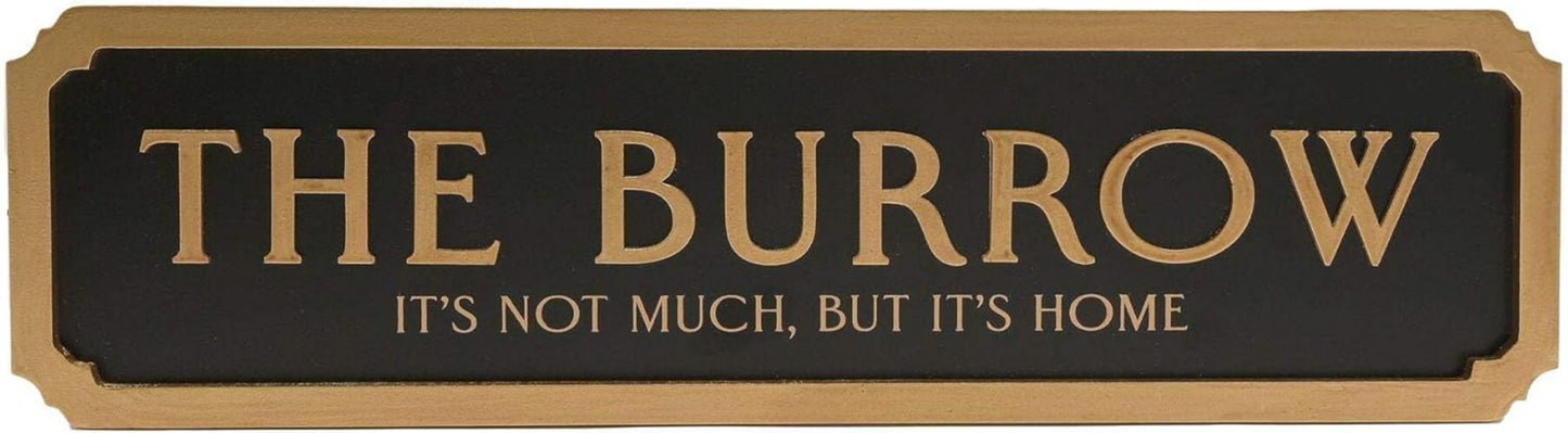 A rectangular black sign with gold lettering that reads “THE BURROW” and smaller text below reading “IT’S NOT MUCH, BUT IT’S HOME,” shown on a plain white background.
