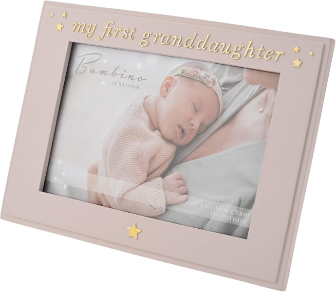 A pale pink picture frame with gold lettering that reads 'my first granddaughter' and gold star accents, shown holding a baby photo print.